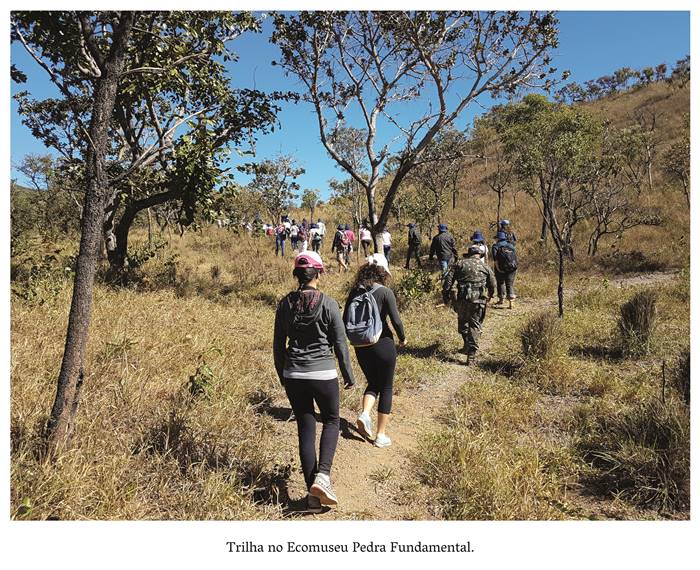  4 v- Trilha no Ecomuseu - Pedra Fundamental Um grupo de pessoas caminha um atrás do outro, seguindo a trilha cercados por arvoredos. Todos trajam roupas esportivas. Realização: Academia Planaltinense de Letras, Artes e Ciências (APLAC), pelo Ecomuseu Pedra Fundamental e pelo Coletivo Nativo Audiodescrição produzida  pelo Instituto de Promoção das Pessoas com Deficiência Visual Audiodescritora: Elma Lúcia Rodrigues Consultor: Fernando Rodrigues Este projeto é promovido com recursos do Fundo de Apoio a Cultura do DF